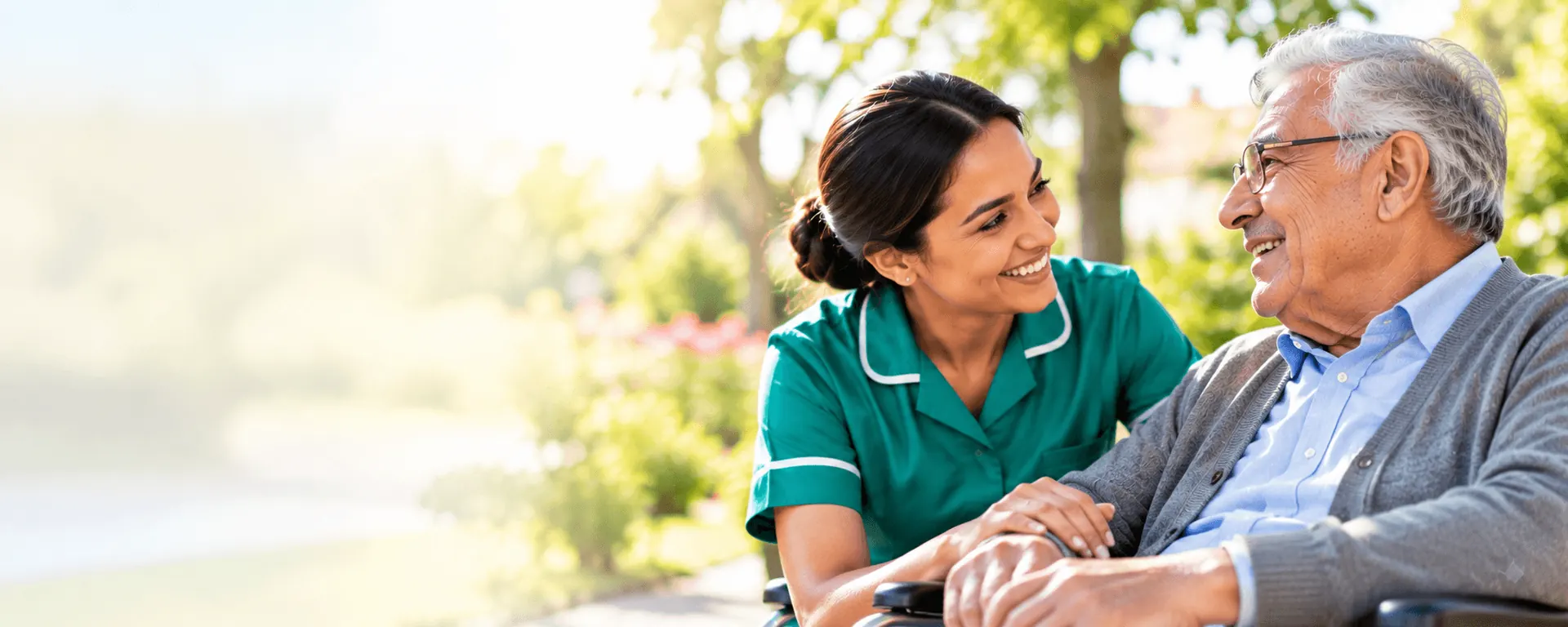 A smiling Nazareth caregiver in a green uniform gently holding the hand of an elderly man outdoors